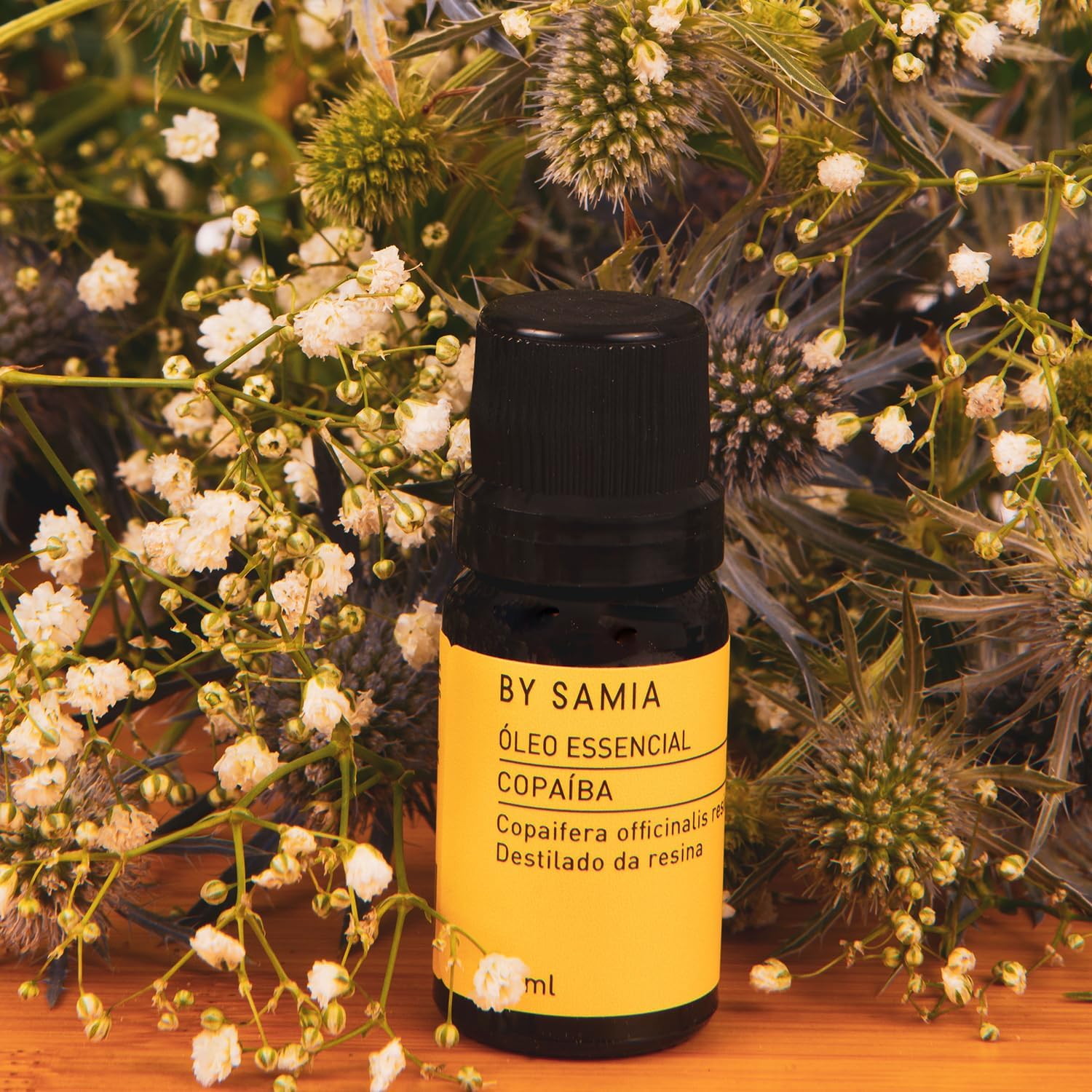 Imagem frontal de um produto com fundo de flores e folhagens naturais em tons verdes e brancos.