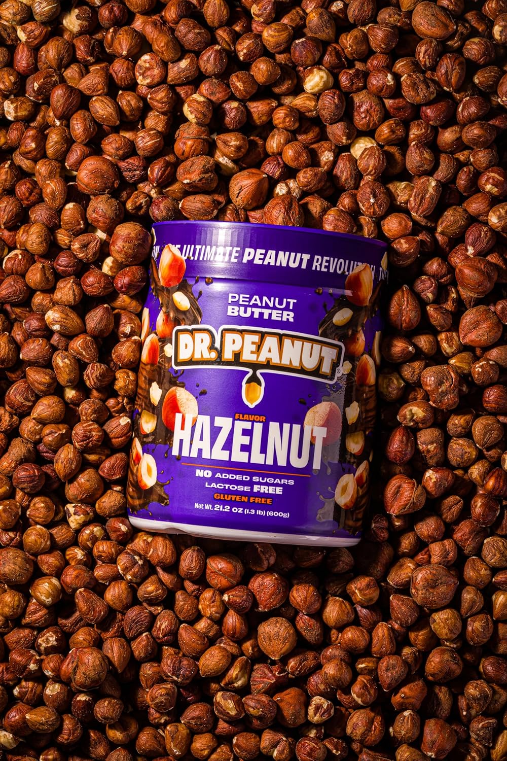 Close-up de pote de creme de avelã sobre fundo coberto por avelãs inteiras, criando um visual uniforme e natural.